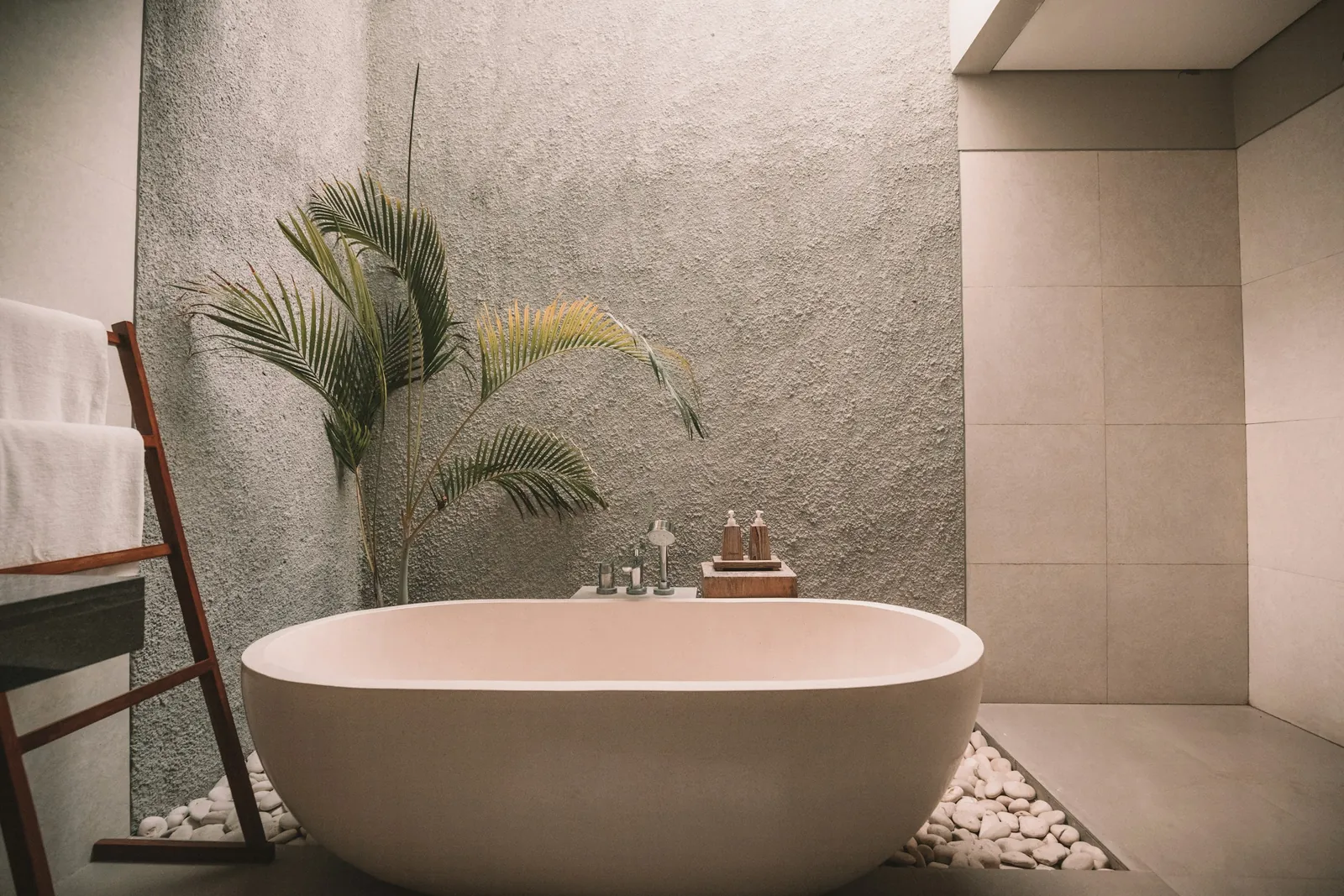 A freestanding stone tub beside a potted palm