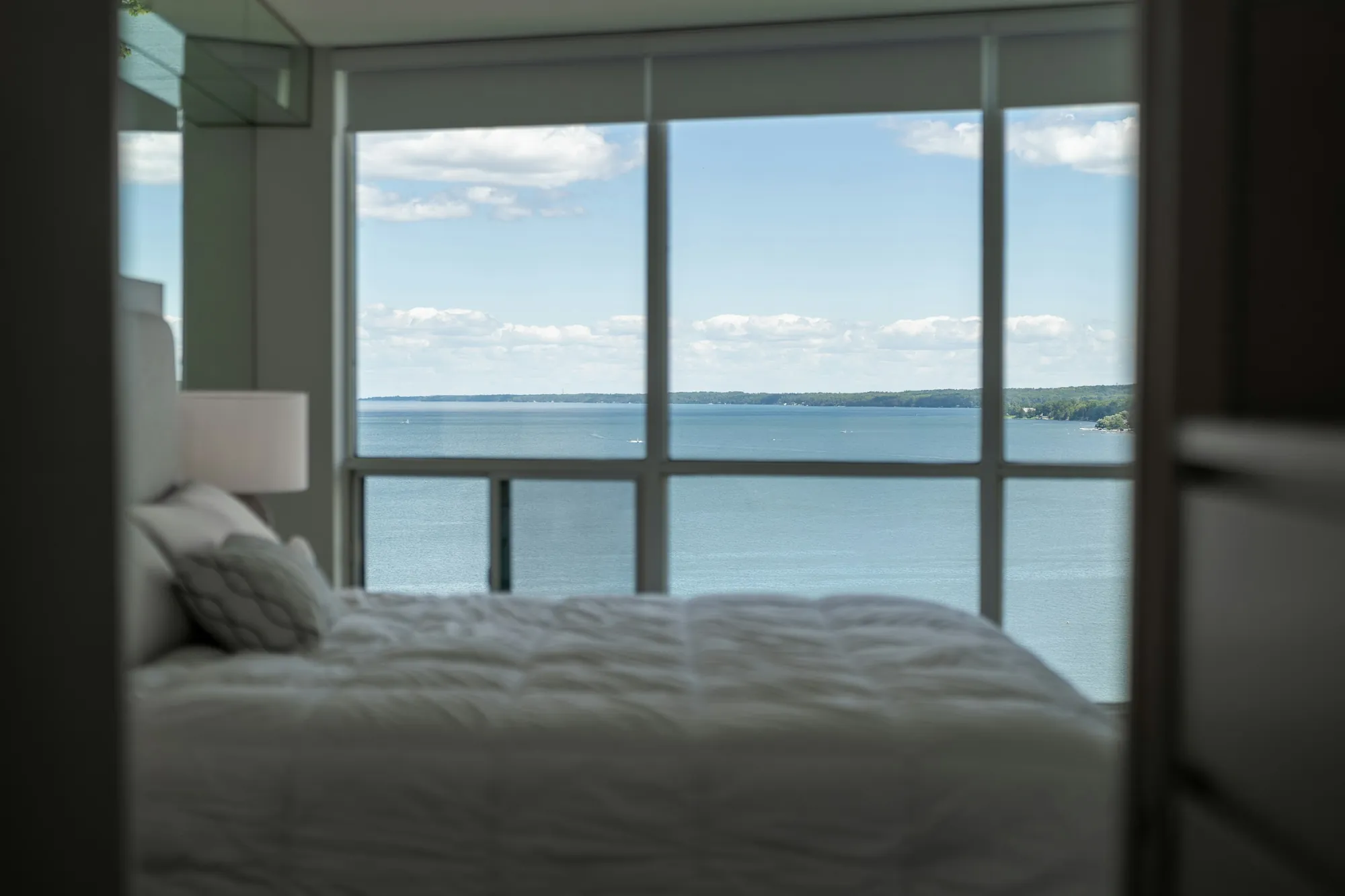 A primary bedroom with a wall of glass to the water