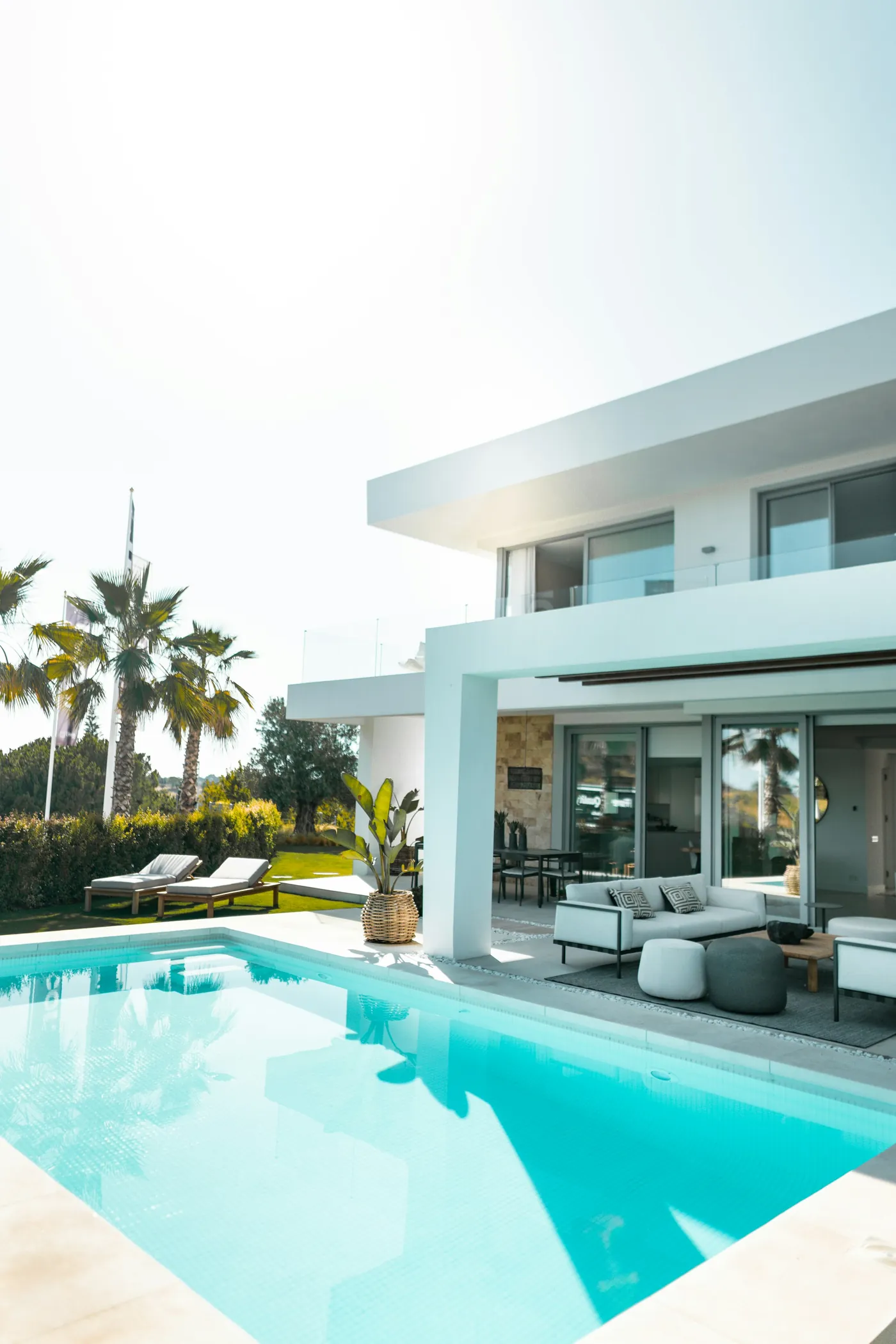 A modern white home with a pool and palms