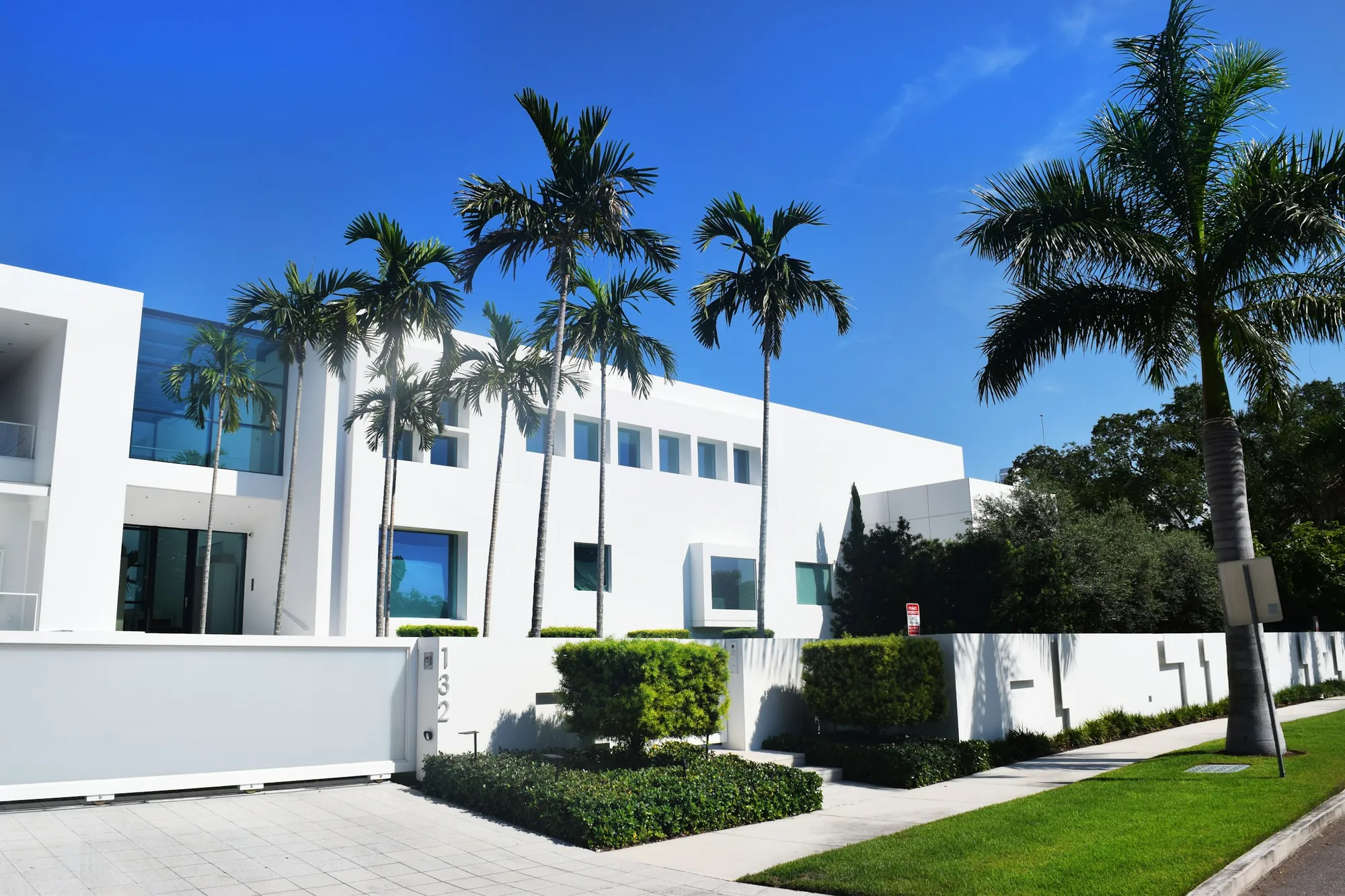 A new white modern home behind palms